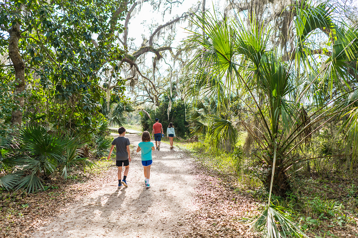 Family walking through a nature trail in St. Petersburg FL during a screen-free summer activity with kids